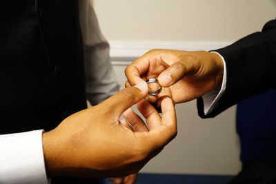 Midsection of gay couple holding wedding ring