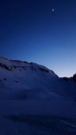 Low angle view of snow covered mountain against blue sky