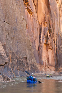 People paddle packrafts below high cliffs on escalante river, utah