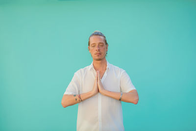 Mature man meditating against blue background