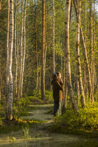 Side view of woman standing in swamp at forest