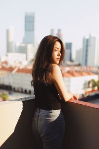 Beautiful young woman standing against cityscape in city