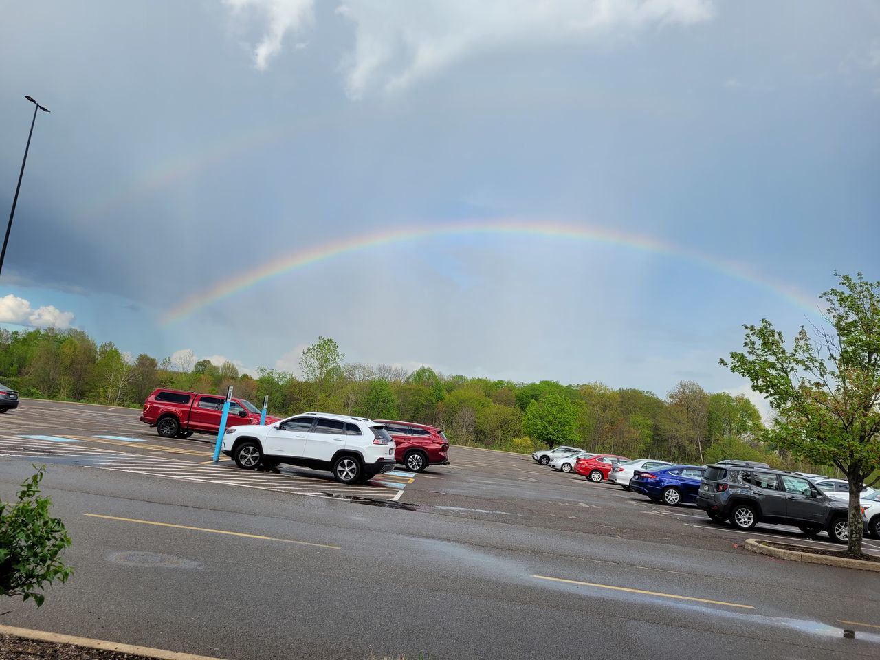 rainbow, transportation, motor vehicle, car, mode of transportation, cloud, road, multi colored, sky, beauty in nature, nature, tree, environment, rain, vehicle, storm, street, plant, double rainbow, land vehicle, city, wet, landscape, scenics - nature, travel, highway, day, dramatic sky, no people, natural phenomenon, motion, architecture, spectrum, storm cloud, outdoors, curve, water, idyllic, traffic, land, red, overcast