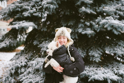 Woman standing on snow covered tree during winter