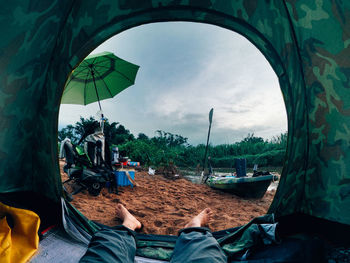 Low section of people relaxing on land against sky