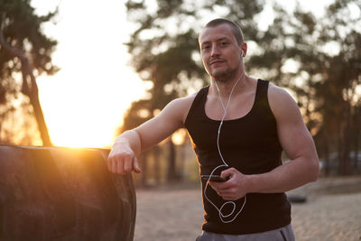 Portrait of young man listening music at beach