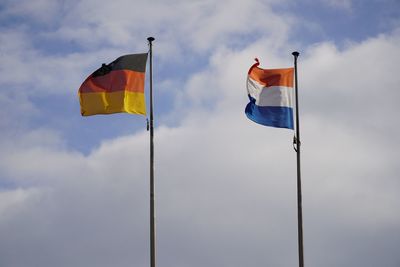 Low angle view of german and dutch flags against sky