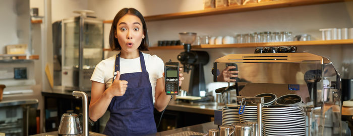 Portrait of young woman standing in kitchen