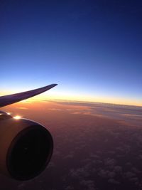 Airplane wing against sky during sunset