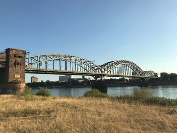 Arch bridge over river against clear blue sky