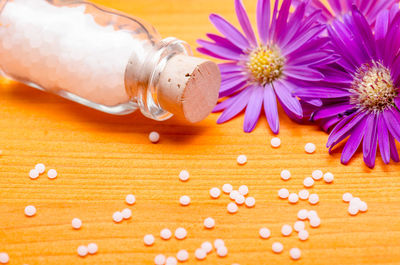 Close-up of homeopathic medicines and flowers on wooden table