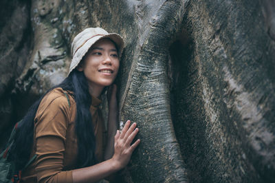 Woman standing by tree trunk