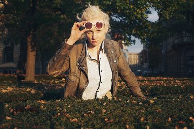 Portrait of young woman wearing sunglasses against trees