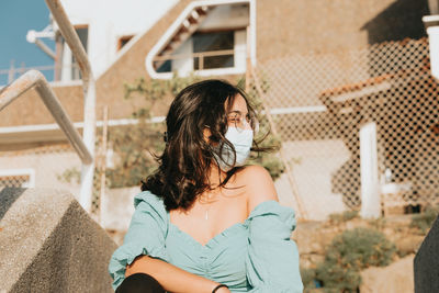 Midsection of woman drinking glass while sitting outdoors