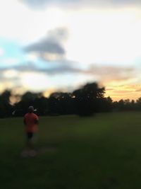 Scenic view of grassy field against sky at sunset