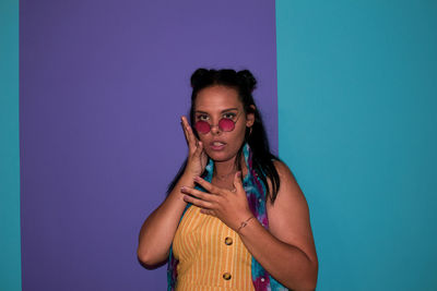 Portrait of young woman standing against blue wall