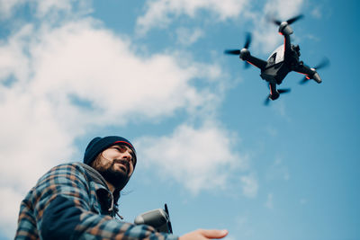 Low angle view of man flying against sky