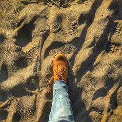 Low section of man standing on sand