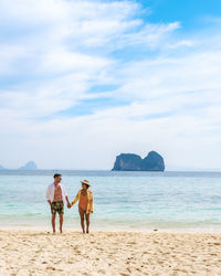 Rear view of woman standing at beach against sky