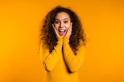 Portrait of a smiling young woman against yellow background