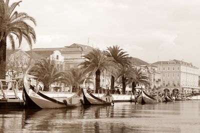 Boats moored in canal by building against sky