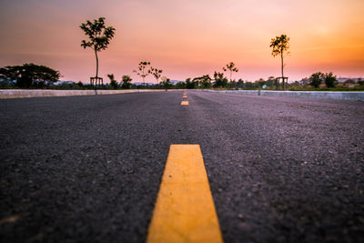 Surface level of road against sky at sunset