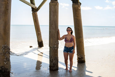 Woman standing below pier at beach