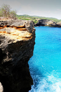 Rock formation in sea against sky