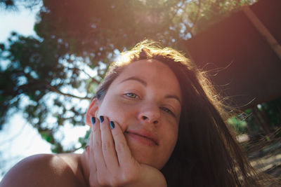 Close-up portrait of young woman against tree