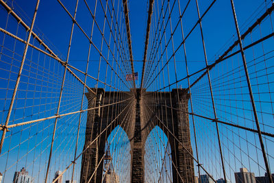 Low angle view of suspension bridge against blue sky