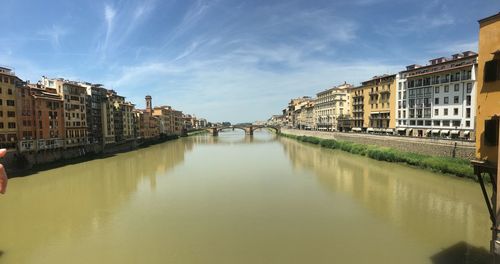 Bridge over river by buildings against sky in city