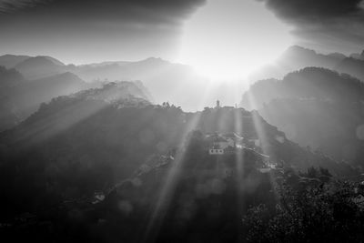 Sunlight streaming through mountains against sky