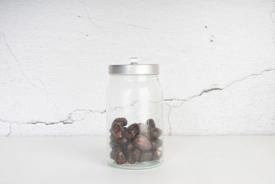 Close-up of glass jar on table against white background