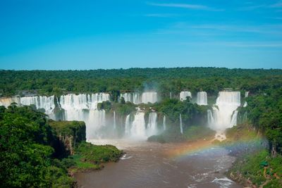 Scenic view of waterfall against clear blue sky