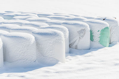 A snow covered haylage bales wrapped in green foil will provide food for farm animals during winter