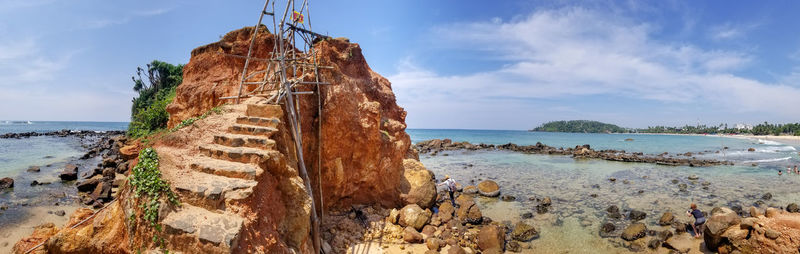 Panoramic view of rocks on beach against sky