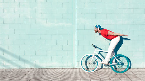 Side view of boy riding bicycle against wall