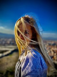 Portrait of woman standing against blue sky