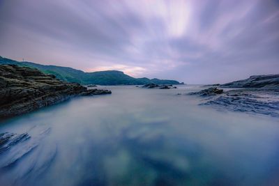 Scenic view of sea by mountains against sky