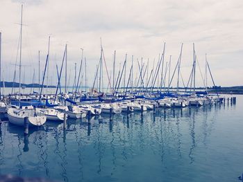 Sailboats moored in sea against sky