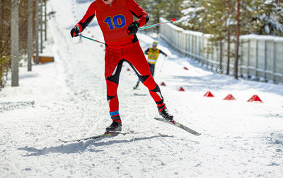 Low section of man skiing on snow covered field