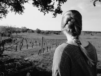 Rear view of woman standing on field against sky