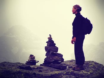 Side view full length of woman standing on mountain at inukshuk