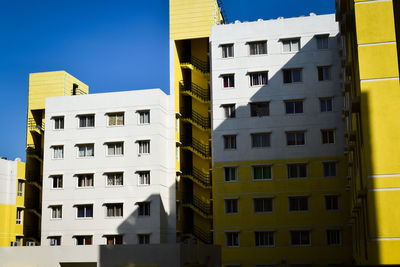 Low angle view of yellow buildings against clear blue sky