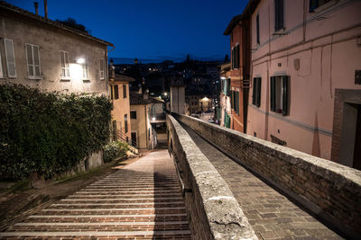 Narrow street amidst buildings in city at night