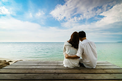 Rear view of couple on shore against sky