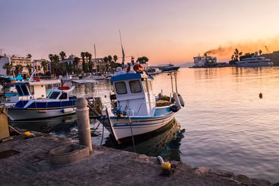 Boats moored at harbor against sky during sunset