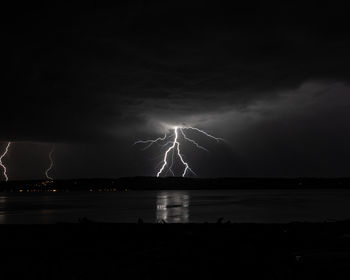 Scenic view of lightning over sea against dramatic sky