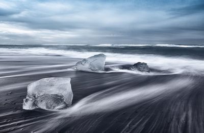 Scenic view of sea against cloudy sky during winter