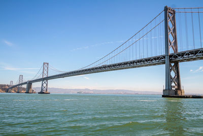 Low angle view of san franciscoñoakland bay bridge over sea against sky